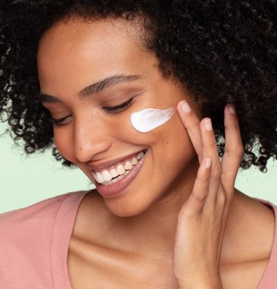 Vrouw die huidverzorgingsproduct op haar gezicht smeert